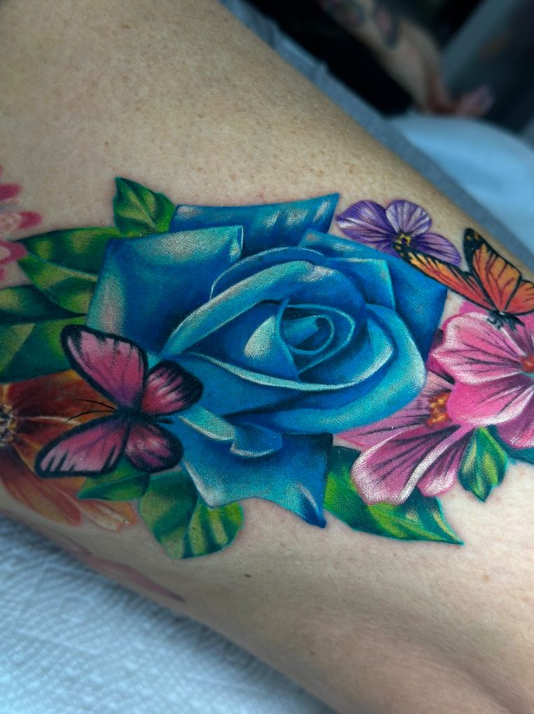 Blue rose and butterflies tattoo on the leg by Tia Berry, colour tattoo artist in Vancouver